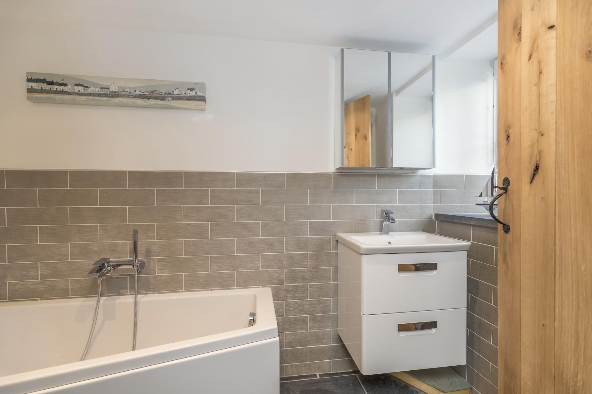 A bathroom with a bathtub, a sink, and a wooden door.