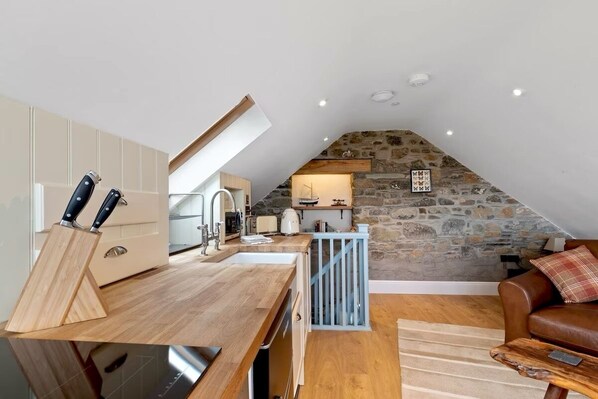 Een gezellige loft-keuken met een stenen muur en een eethoek van hout.