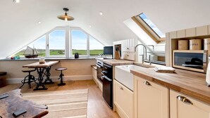 Una cocina moderna con un ventanal grande, un comedor con mesa y sillas, y vistas al campo.