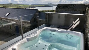 Un jacuzzi en un balcón con vistas al mar y a las colinas.