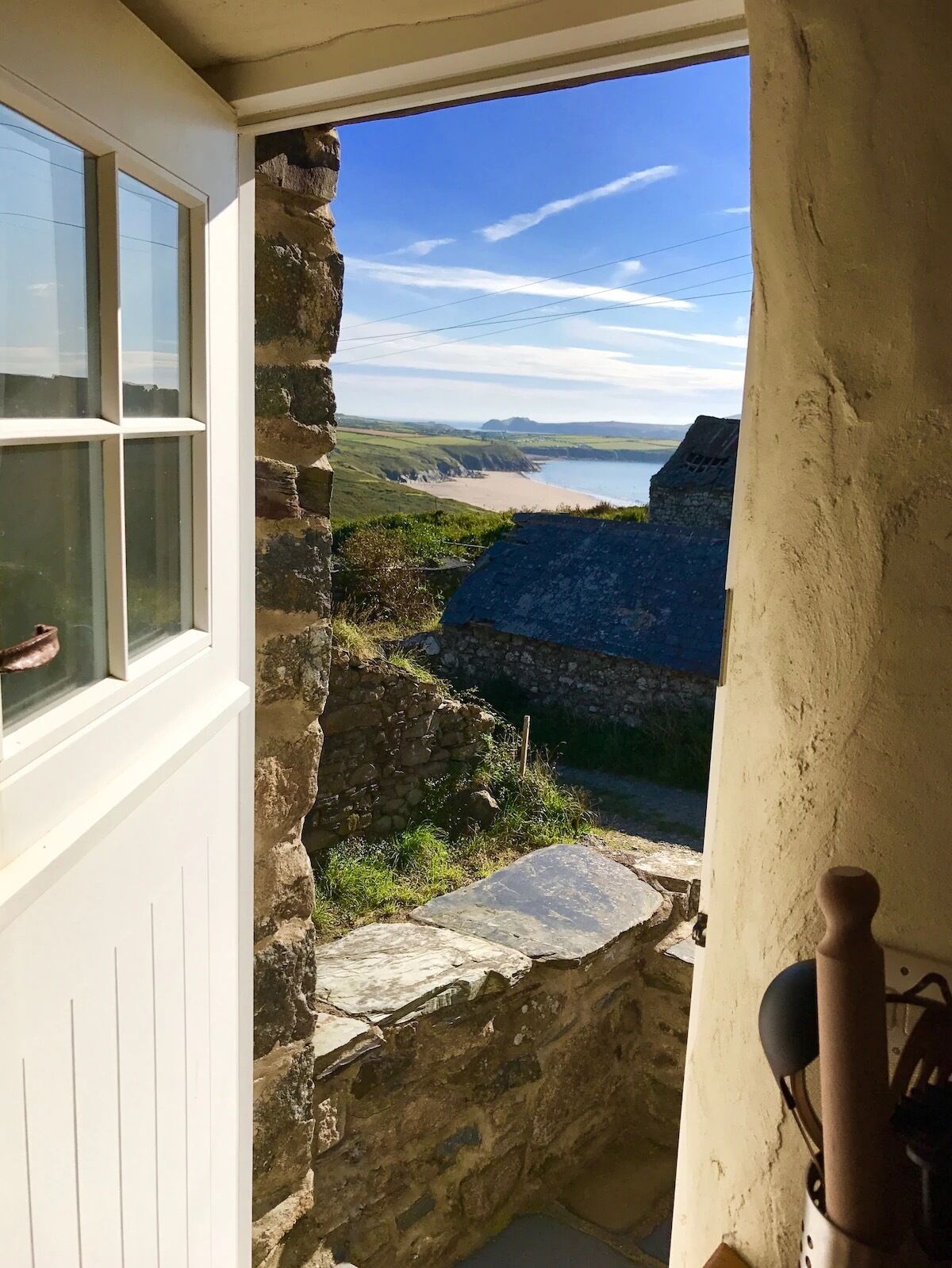 A stone doorway leading to a scenic view of a beach and cliffs.