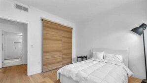 Une chambre à coucher avec un grand lit, une table de chevet, une lampe et une armoire en bois à portes coulissantes.