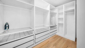 Un dressing spacieux doté de nombreuses étagères et de tiroirs, d’un plancher en bois et d’un puits de lumière.