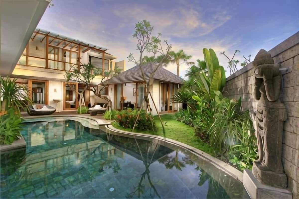 A modern house with a swimming pool, a small garden, and a stone wall.