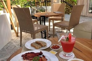 A dining table with plates of food, a glass of red beverage, and a small bowl of sauce.