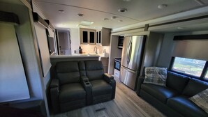 A compact living space with a kitchenette, a sofa, and a dining area. - Luxurious RV (Virginia Beach)
