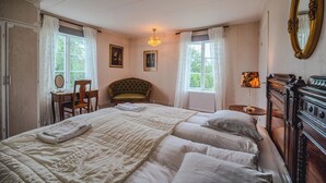 Un dormitorio amplio con una cama grande, un aparador de madera, una silla y un escritorio.