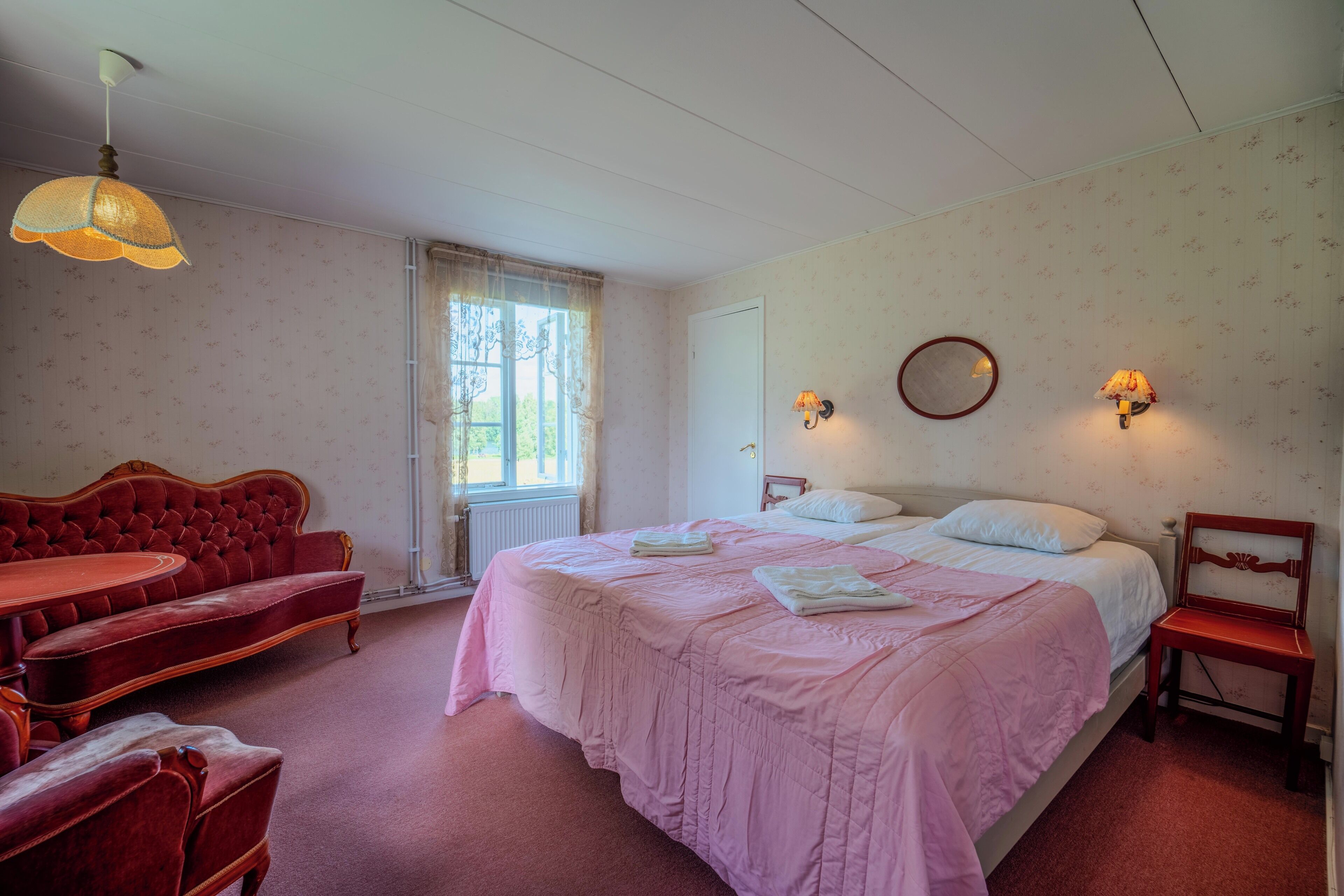 Un dormitorio con una cama grande, un sofá rojo, una silla de madera y una mesita.