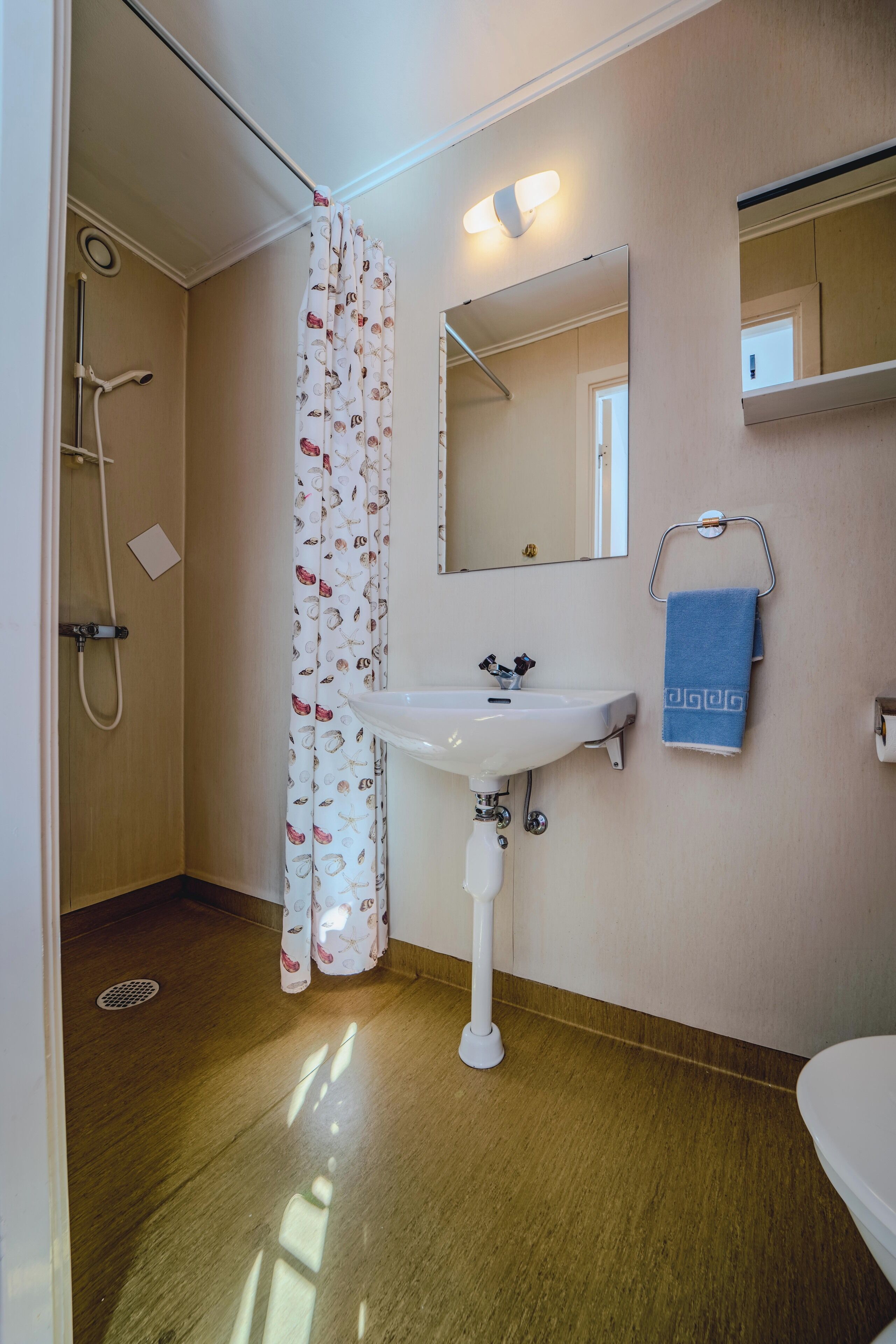 A bathroom with a shower, a sink, a mirror, and a towel rack.