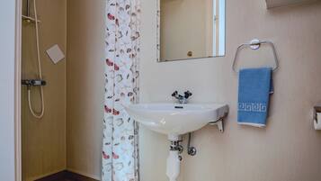 A bathroom with a shower, a sink, a mirror, and a towel rack.