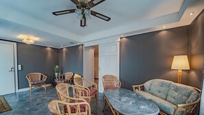 Una habitación con una mesa de comedor, sillas de mimbre, un sofá, un ventilador de techo y una araña.