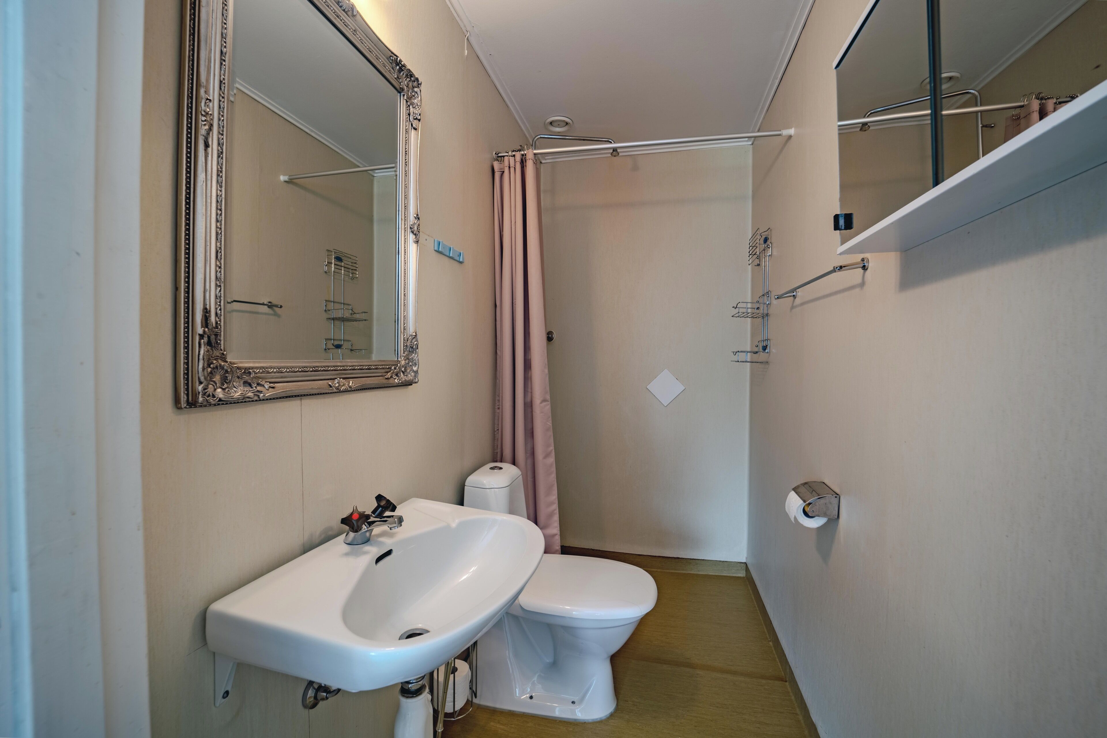 A compact bathroom with a white sink, toilet, and shower area.