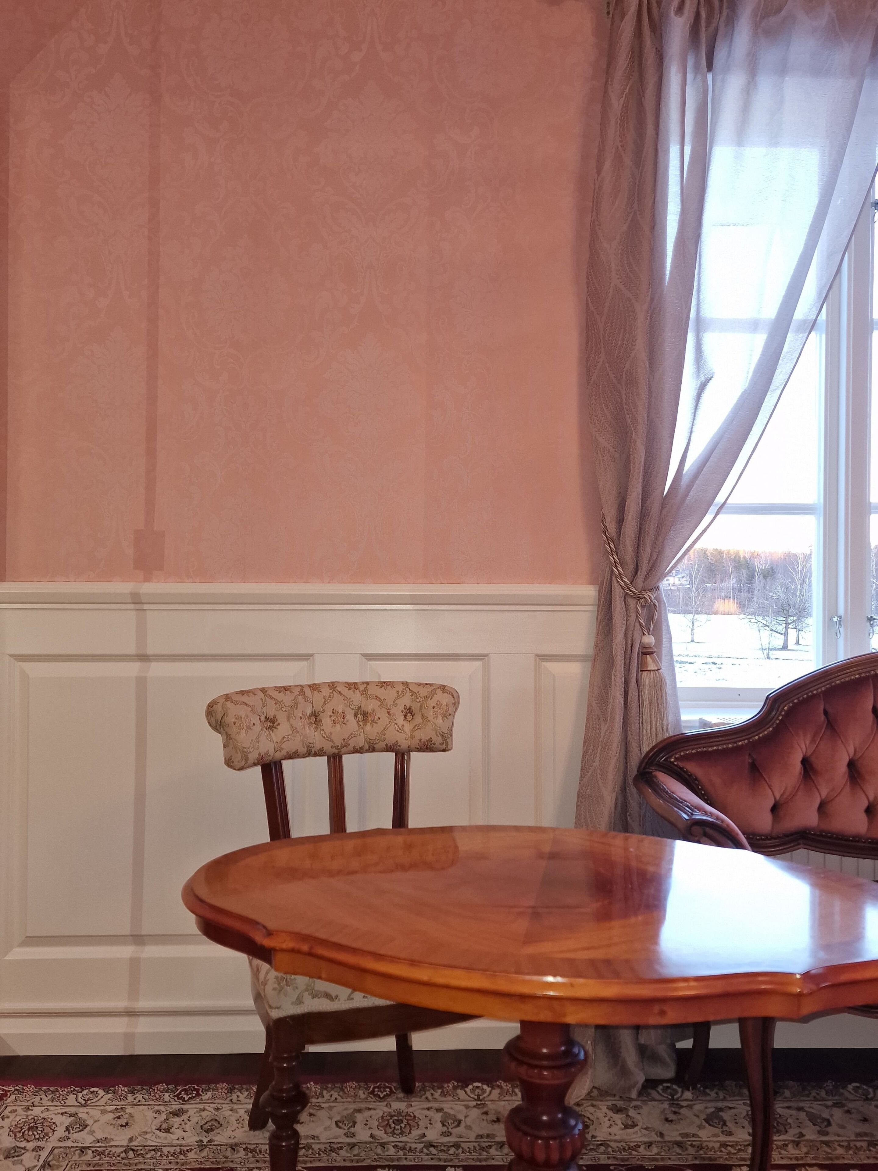 A dining area with a wooden table and two chairs, one with a floral pattern.
