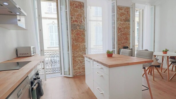Una cocina moderna con encimera de madera, armarios blancos y horno integrado.