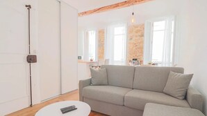 Una sala de estar moderna con un sofá gris, una mesita blanca y piso de madera.