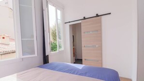 Un dormitorio con una cama, una puerta corredera y una ventana.