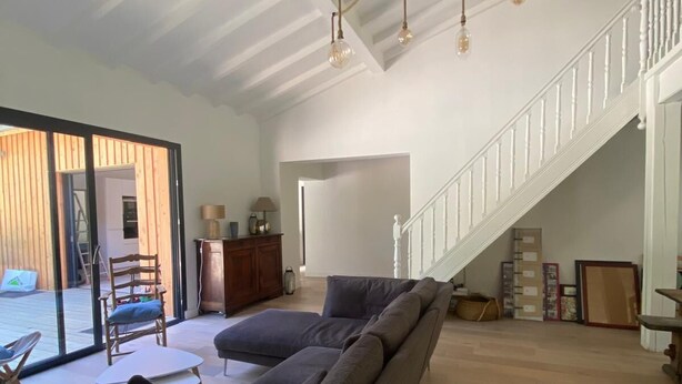 Ein geräumiges Wohnzimmer mit einer großen Eckcouch, einem Esstisch und einer Treppe, die in eine obere Ebene führt.