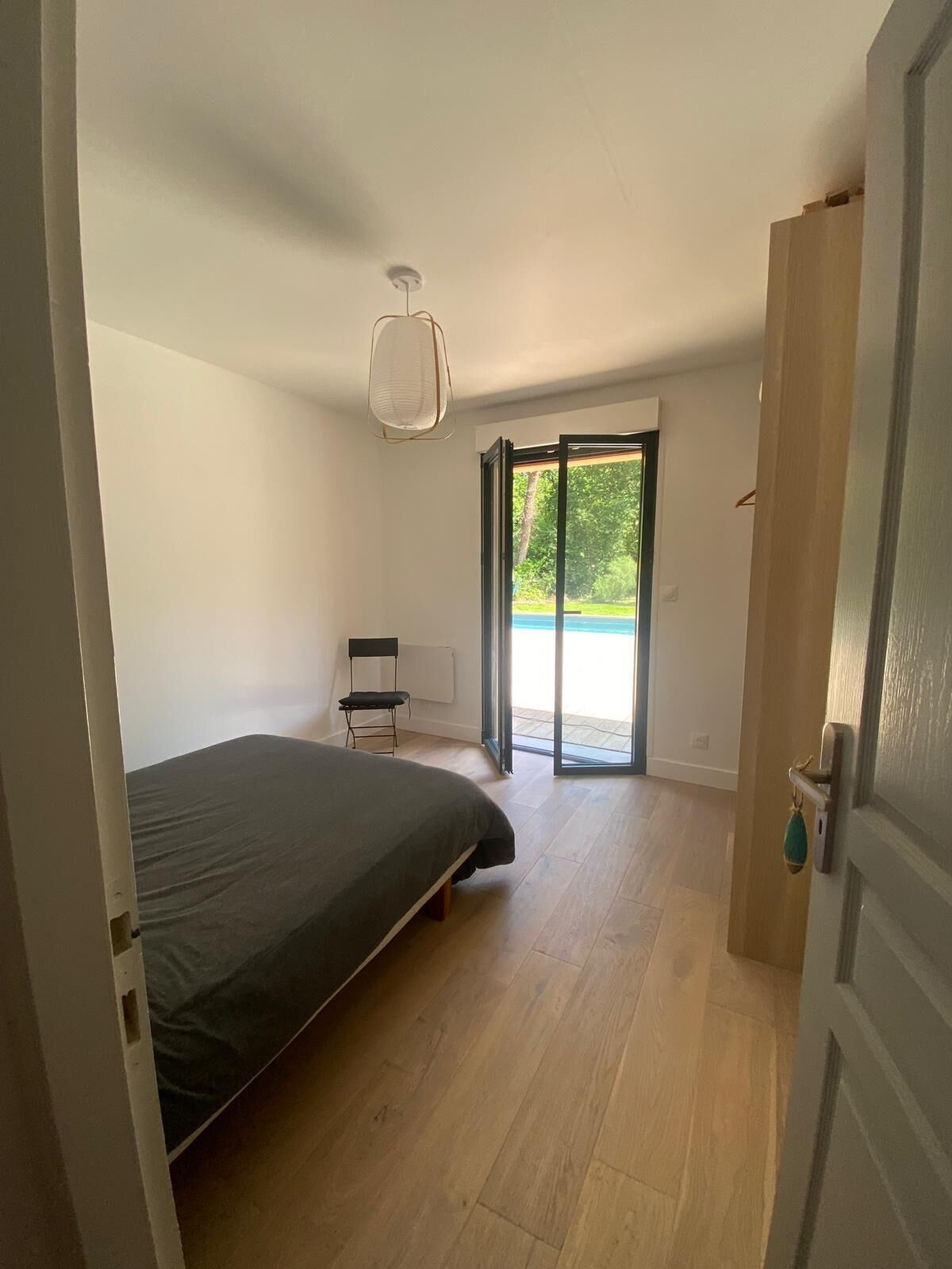 Un dormitorio con cama, una silla, ventana y puerta.