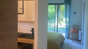 Ein modernes Schlafzimmer mit einem Bett, einem Sessel und Blick auf Grün.