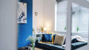 A modern living room with a sofa, a coffee table, and a wall-mounted abstract painting. - Incredible Home | 3Bedrooms | Driveway | Sleeps 6 (Lancashire)