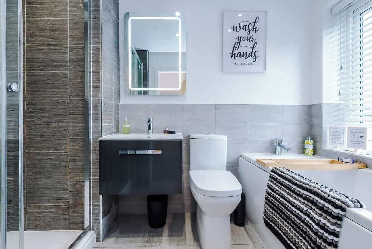 Un baño moderno con cabina de ducha de vidrio, inodoro blanco, tocador negro y barra para toallas.