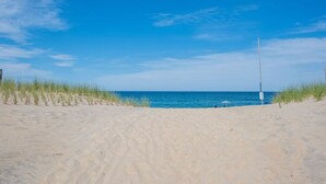 Une plage avec des dunes de sable et un ciel bleu dégagé.