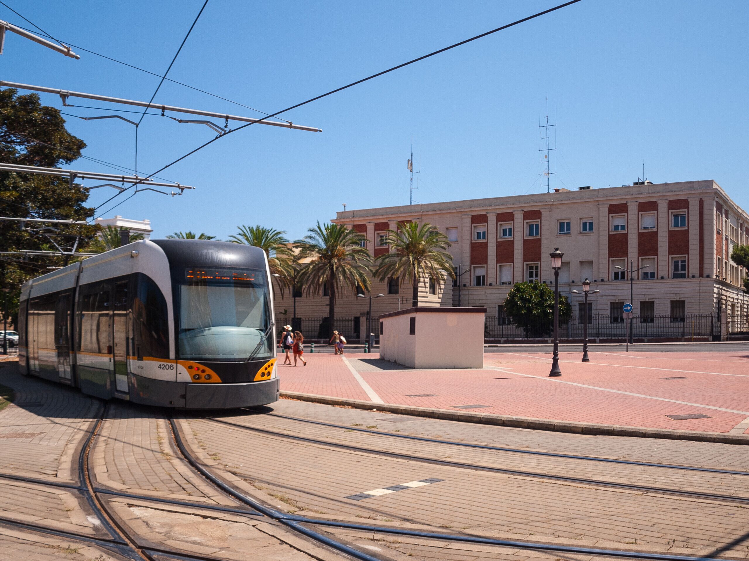 Un tramway circule sur des rails, avec un bâtiment en arrière-plan.