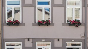 Un edificio de dos pisos con tres ventanas en la planta baja, cada una con una jardinera.