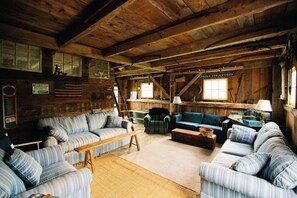 A rustic wooden interior with striped sofas, a wooden coffee table, and a ladder.
