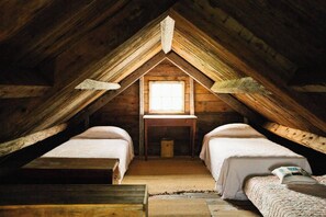 Pequeña habitación en el ático con dos camas, una ventana y un escritorio de madera.