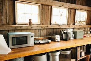 Una cocina con encimera de madera, microondas, tostadora, cafetera y ventana con vistas.