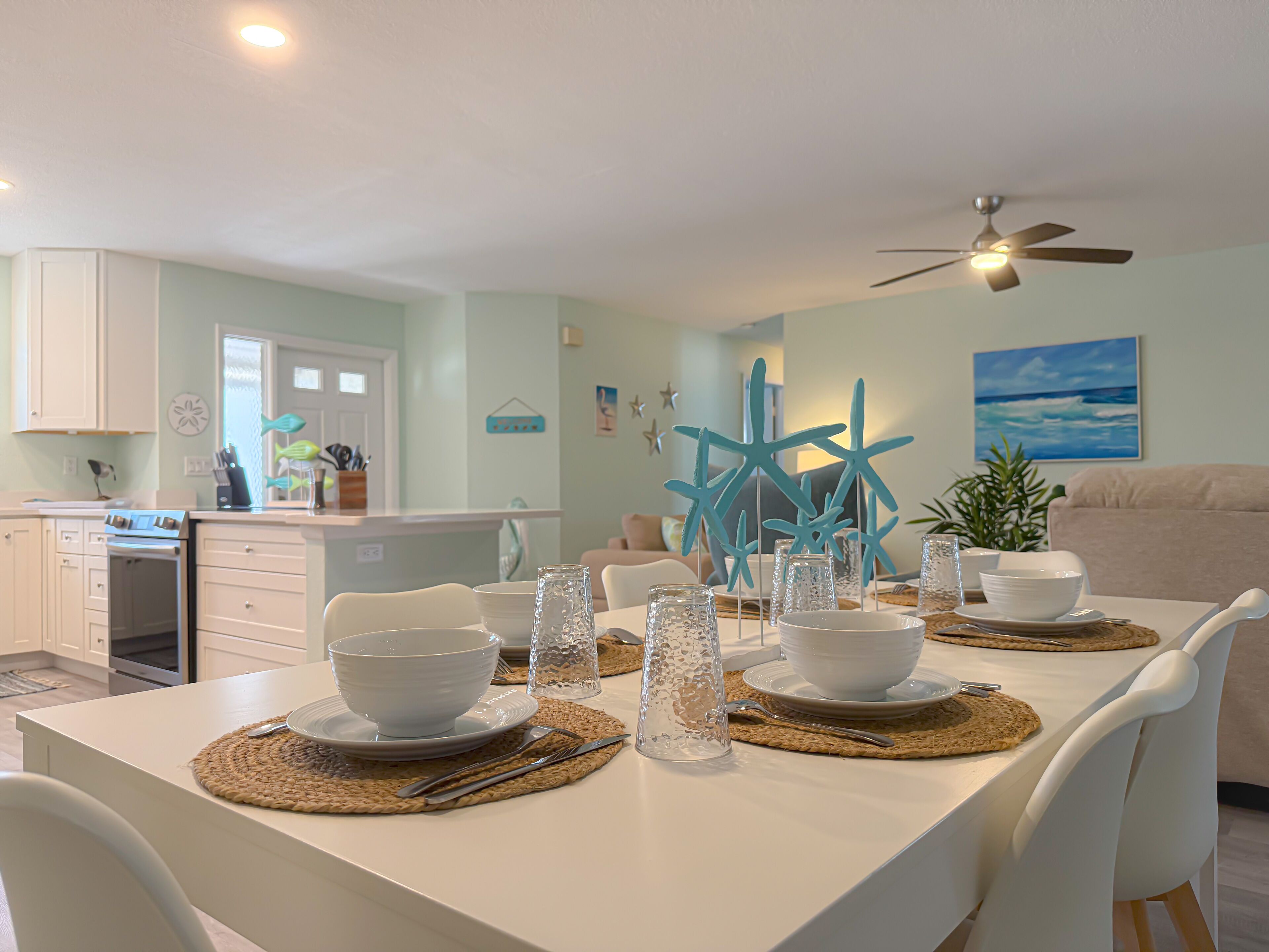 A dining area with a white table set for four, starfish decorations, and a ceiling fan.
