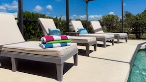 Un espace de détente extérieur abrité, doté de chaises longues et d’une piscine.