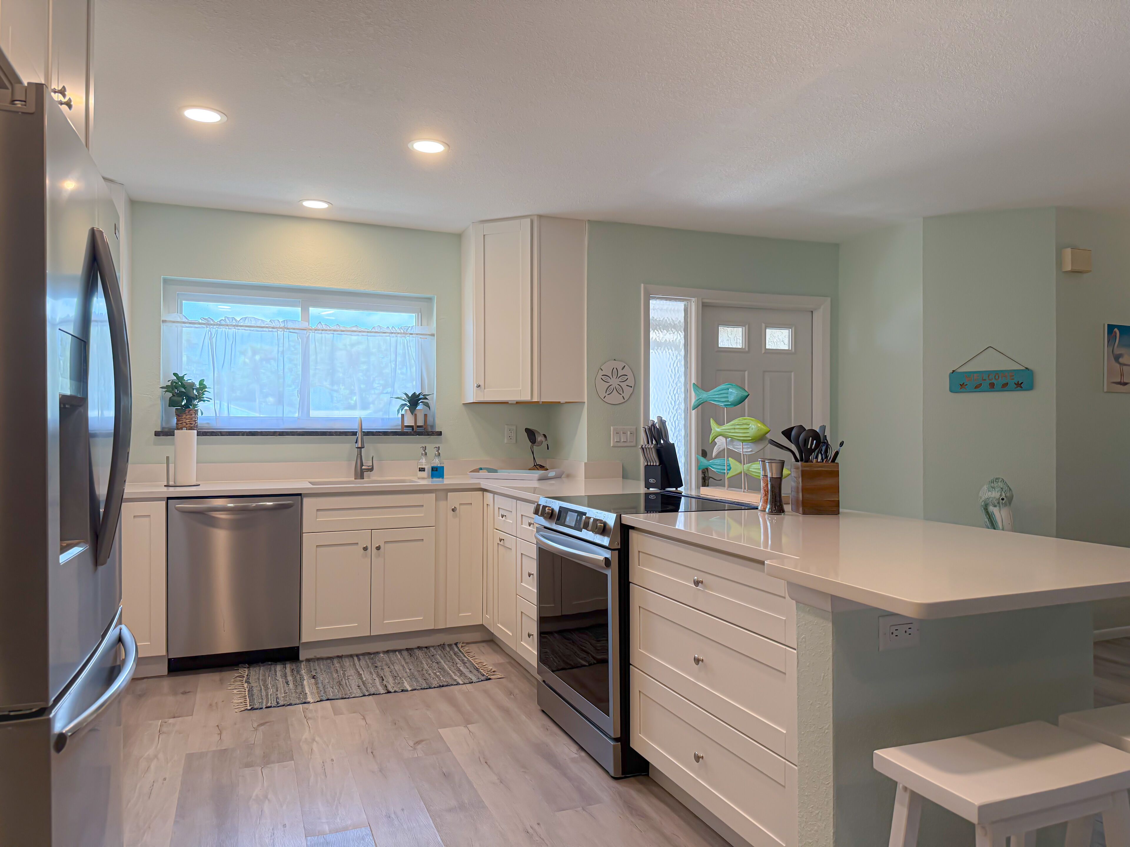 A modern kitchen with white cabinets, stainless steel appliances, a built-in oven, and a window with a view.