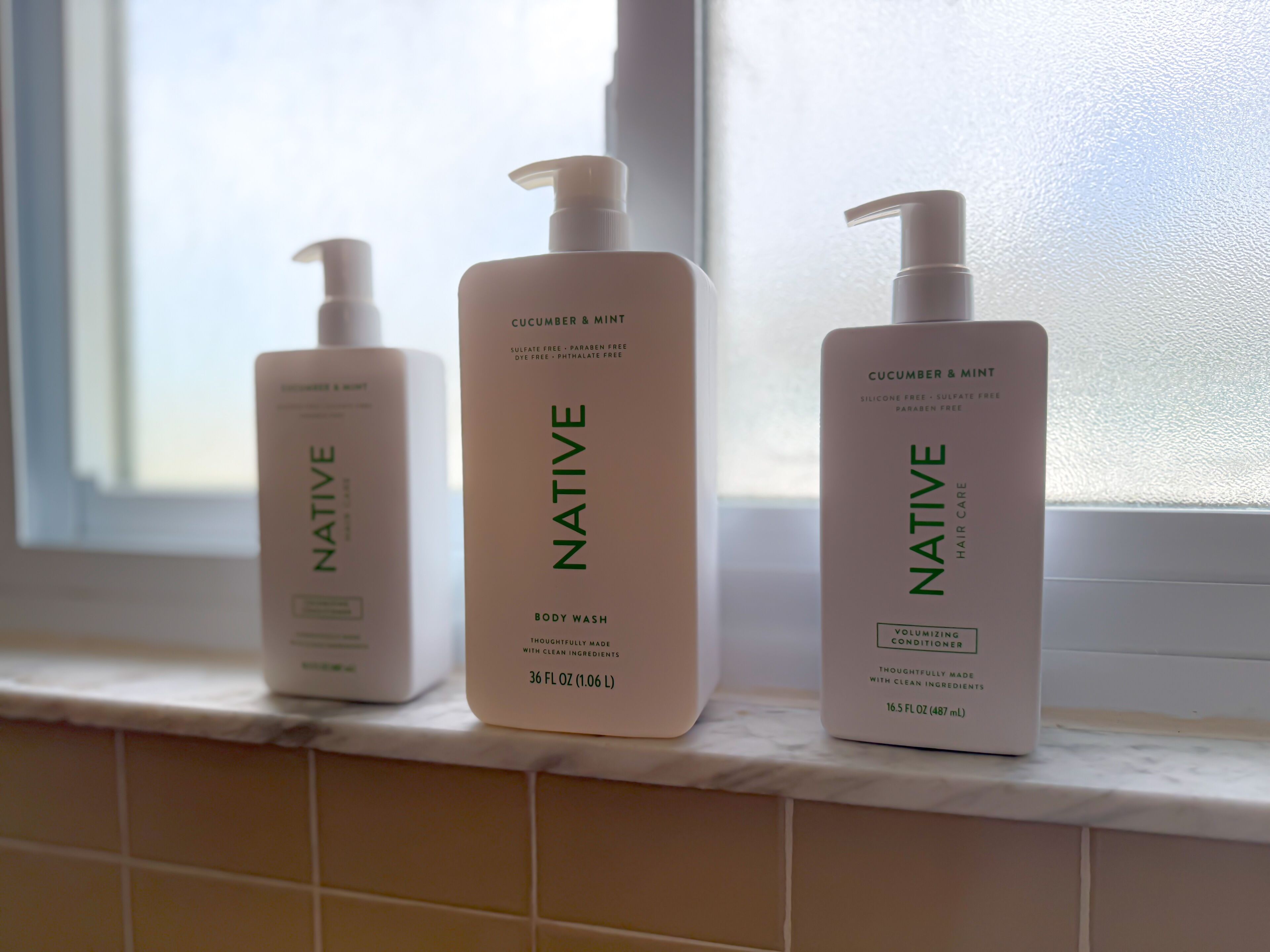 Three bottles of Native body wash on a bathroom counter.