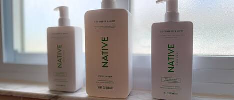 Three bottles of Native body wash on a bathroom counter.