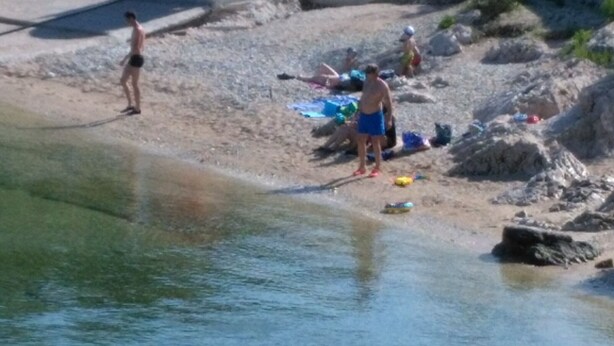 Eine Strandansicht mit Menschen und Strandausrüstung.