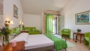 A bedroom with a bed, green chairs, a small table, and a painting on the wall. - Double Bedroom with Balcony (Drvenik Veliki)