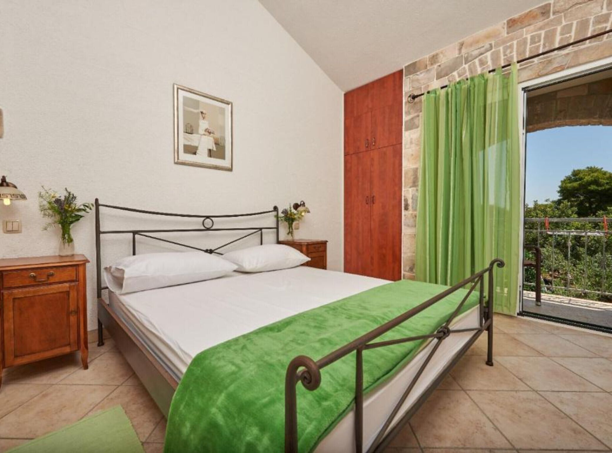 A bedroom with a bed, a nightstand, a dresser, a framed picture on the wall, and a green curtain.