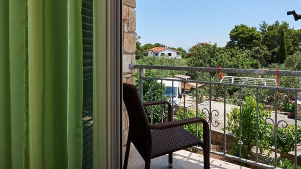 A balcony with a stone wall, a metal railing, and a chair. - Double Bedroom with Balcony (Drvenik Veliki)