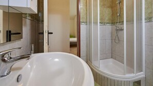 A bathroom with a white sink, a shower with a glass door, and a mirror. - Double Bedroom with Balcony (Drvenik Veliki)