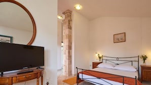 Quarto com cama, mesa de cabeceira, televisão e um espelho grande.
