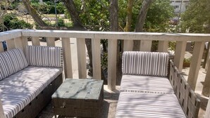 A balcony with two striped sofas and a small table, surrounded by a wooden railing. - One Bedroom Apartment with Balcony (Sutivan)