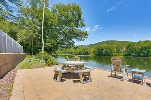 An outdoor patio with a table and chairs, a small table, and a view of a lake and forest. - [City] Farm w/ 120 Acres, Mtn & Water Views! (Damascus)