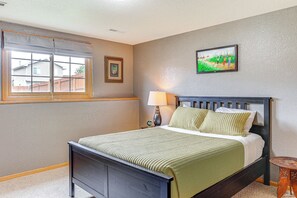 Una camera da letto con un letto, una finestra vista casa, una lampada e un quadro appeso al muro.