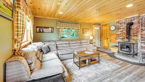 Ein gemütliches Wohnzimmer mit einer Eckcouch, einem Kamin und einer Holzbalkendecke.