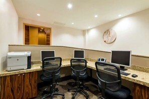 Une salle de conférence équipée de trois bureaux, chacun comprenant un écran d’ordinateur, une imprimante et une chaise.