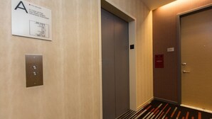 An elevator with a sign indicating use of stairs in case of fire, a door with a number plate, and a carpeted floor. - New York City | Midtown Escape | Near Central Park & Broadway (New York)