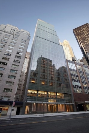 Un edificio moderno de gran altura con fachada de vidrio, rodeado de otros edificios altos.