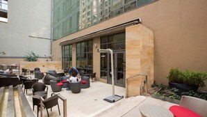 A modern outdoor seating area with wicker furniture and a glass door entrance. - New York City | Midtown Escape | Near Central Park & Broadway (New York)